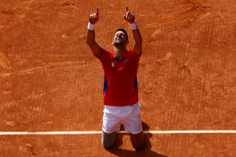 Reuters/Edgar Su/Proibida reprodução Paris 2024 Olympics - Tennis - Men's Singles Gold Medal Match - Roland-Garros Stadium, Paris, France - August 04, 2024. Novak Djokovic of Serbia celebrates after winning gold against Carlos Alcaraz of Spain. Reuters/Edgar Su/Proibida reprodução